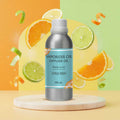 Veena Citrus Fresh Vaporizer and Diffuser Oil 100ml bottle on a round marble podium with flying orange and lime slices in the background.