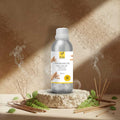 Veena Sandalwood Premium Vaporizer and Diffuser Oil 100ml aluminum bottle standing on a rustic stone podium surrounded by burning incense sticks.