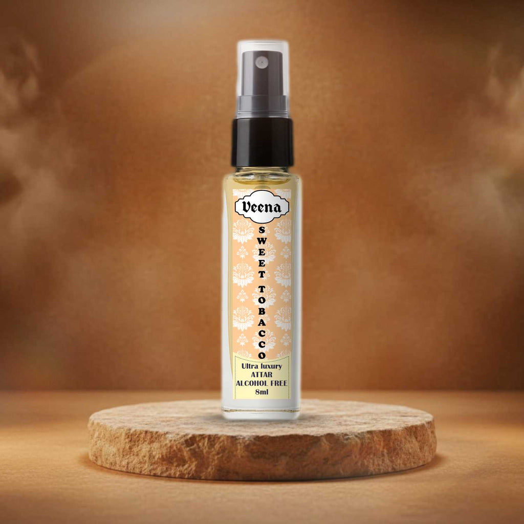 Veena Sweet Tobacco original 100% alcohol-free 8ml perfume spray bottle presented beautifully on a rough-cut natural sand stone slice podium with warm amber background styling.