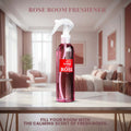 Veena Rose premium room freshener spray bottle displayed on a white marble table inside a luxury rose-toned bedroom layout.