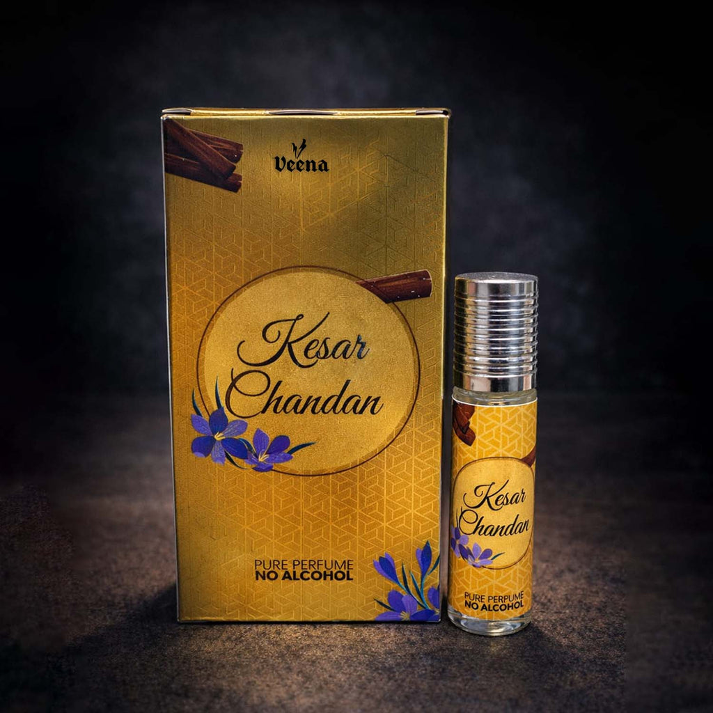 Veena luxury Kesar Chandan perfume oil pocket roll-on standing next to its premium gold presentation box adorned with saffron flowers and sandalwood logs.