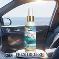 Veena Fresh Breeze Premium Car Air Freshner Mist 100ml (3.38 fl.oz.) spray bottle showcased on a white pedestal inside a car interior, with a bright ocean beach scenic view visible through the side window.