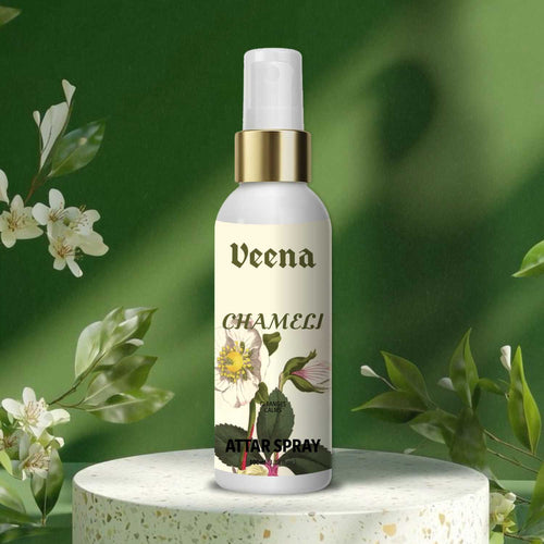 Veena Chameli premium attar spray 100ml bottle with a gold collar displayed on a stone terrazzo podium with a fresh green background.