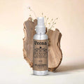 Veena Sandalwood alcohol-free attar spray 100ml bottle showcased against a natural light wood slice backdrop.