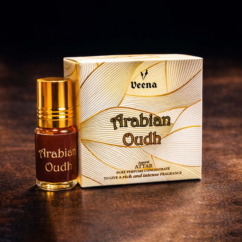 Veena Arabian Oudh premium apparel attar concentrate bottle standing next to its luxury cream and gold golden-wave presentation gift box.