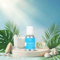 Veena Summer Breeze Fragrance for Candle Making bottle showcased on a round stone podium flanked by tropical palm leaves, seashells, and clear liquid ingredients.