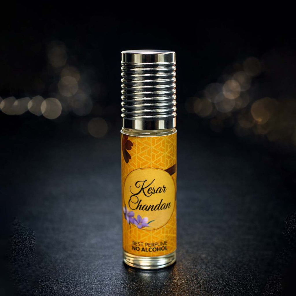 Veena Kesar Chandan premium non-alcoholic perfume oil roll-on bottle with a golden geometric label and ribbed silver cap against a dark bokeh background.