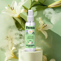 Veena Attar Phool alcohol-free spray 100ml bottle on a podium surrounded by white lilies and cinematic soft smoke.