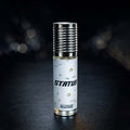 Veena Status premium non-alcoholic perfume oil roll-on bottle with a textured silver cap resting against a dark bokeh background.