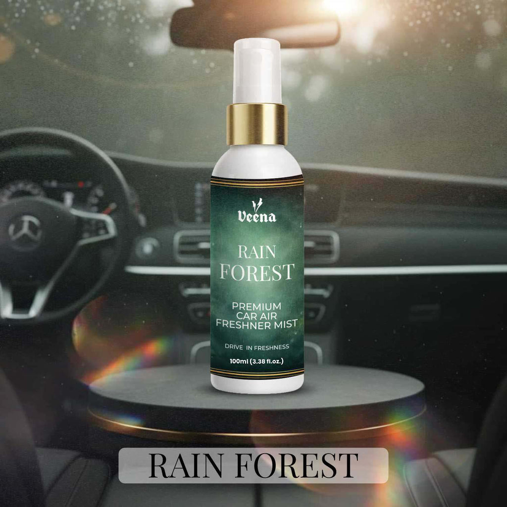 Veena Rain Forest Premium Car Air Freshner Mist 100ml bottle sitting on a sleek dark pedestal inside a modern steering-wheel dashboard environment.