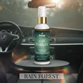 Veena Rain Forest Premium Car Air Freshner Mist 100ml bottle sitting on a sleek dark pedestal inside a modern steering-wheel dashboard environment.