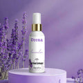Veena Lavender premium attar spray 100ml bottle with a gold collar displayed on a luxury purple round podium with fresh lavender flowers in the background.