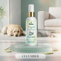 Veena Cucumber Pet Perfume for Dogs and Cats 100ml spray bottle resting on a frosted glass podium with scattered cucumber slices, featuring a Golden Retriever dog in a bright room background.