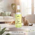 Veena Lemongrass Pet Perfume for Dogs and Cats 100ml spray bottle positioned on a round pedestal with a fluffy British Shorthair cat sitting peacefully in a sunlit home setting.