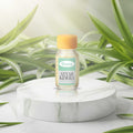 Veena Premium Attar Kewra 2ml miniature glass bottle standing on clean white marble podium with soft green leaf graphics background