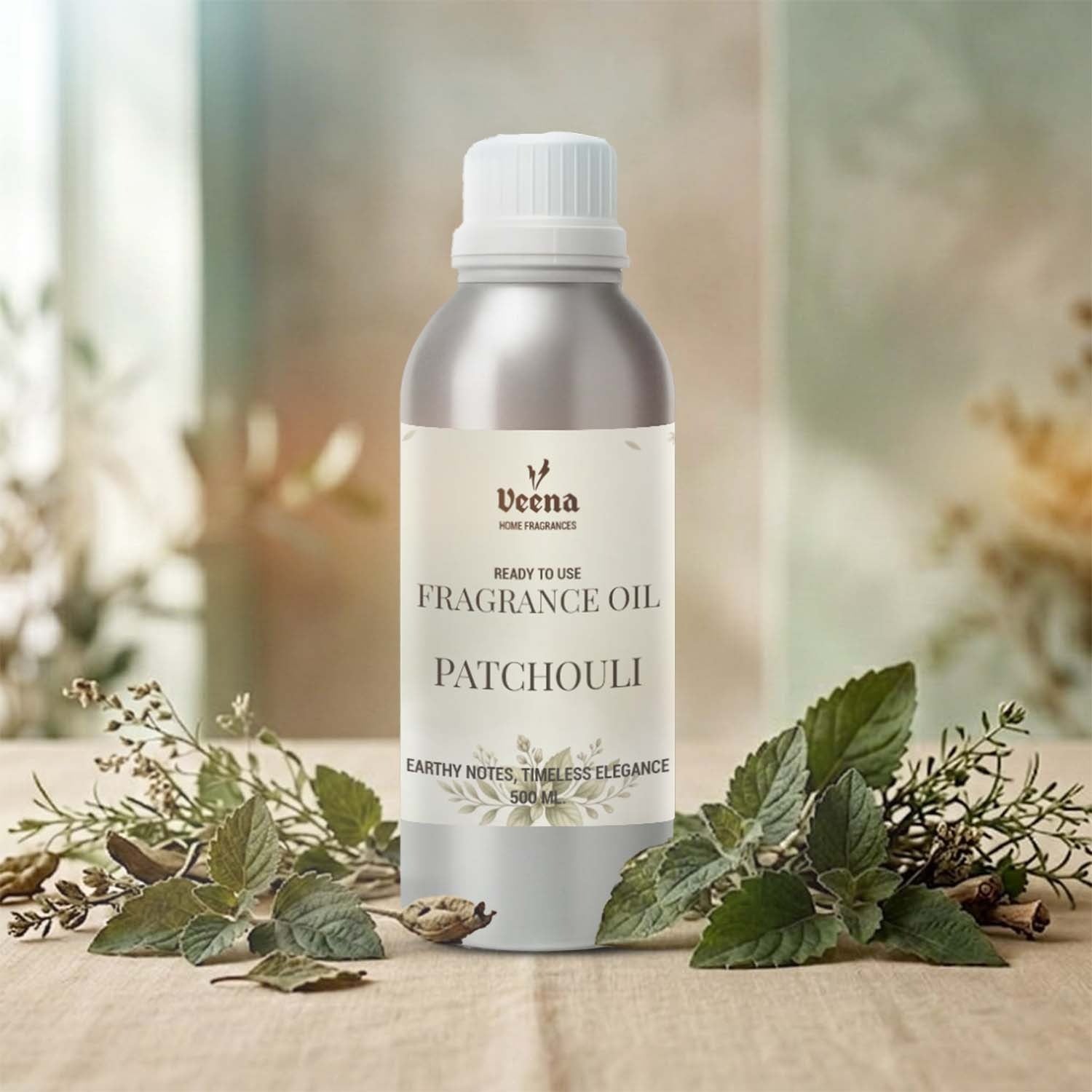 Veena Home Fragrances 500ml Patchouli Fragrance Oil aluminum bottle on a wooden table surrounded by green patchouli leaves.