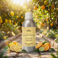 Veena Home Fragrances 500ml Citrus Fresh Fragrance Oil aluminum bottle on a brick pathway surrounded by lemons, oranges, and a sunlit orchard background.