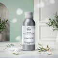 Veena Home Fragrances 500ml Camphor Fragrance Oil aluminum bottle on a table with a calm green arch and soft shadow background.