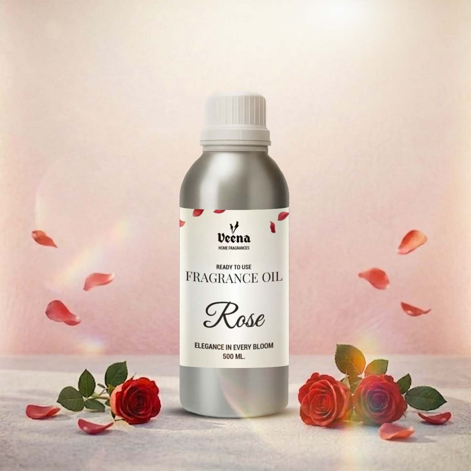 Veena Home Fragrances 500ml Rose Fragrance Oil aluminum bottle on a soft surface surrounded by fresh red roses and falling petals with a warm light background.