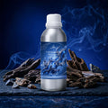 Veena Blue Oudh Premium Vaporizer and Diffuser Oil silver aluminum bottle with deep indigo agarwood label surrounded by natural wood pieces and smoke