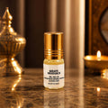 Khatu Shayam Ji 2ml concentrated apparel perfume roll-on bottle centered on a glossy counter next to a burning diya candle.