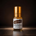 White Oudh 2ml concentrated apparel perfume roll-on glass bottle with a golden cap against a dark brown backdrop.