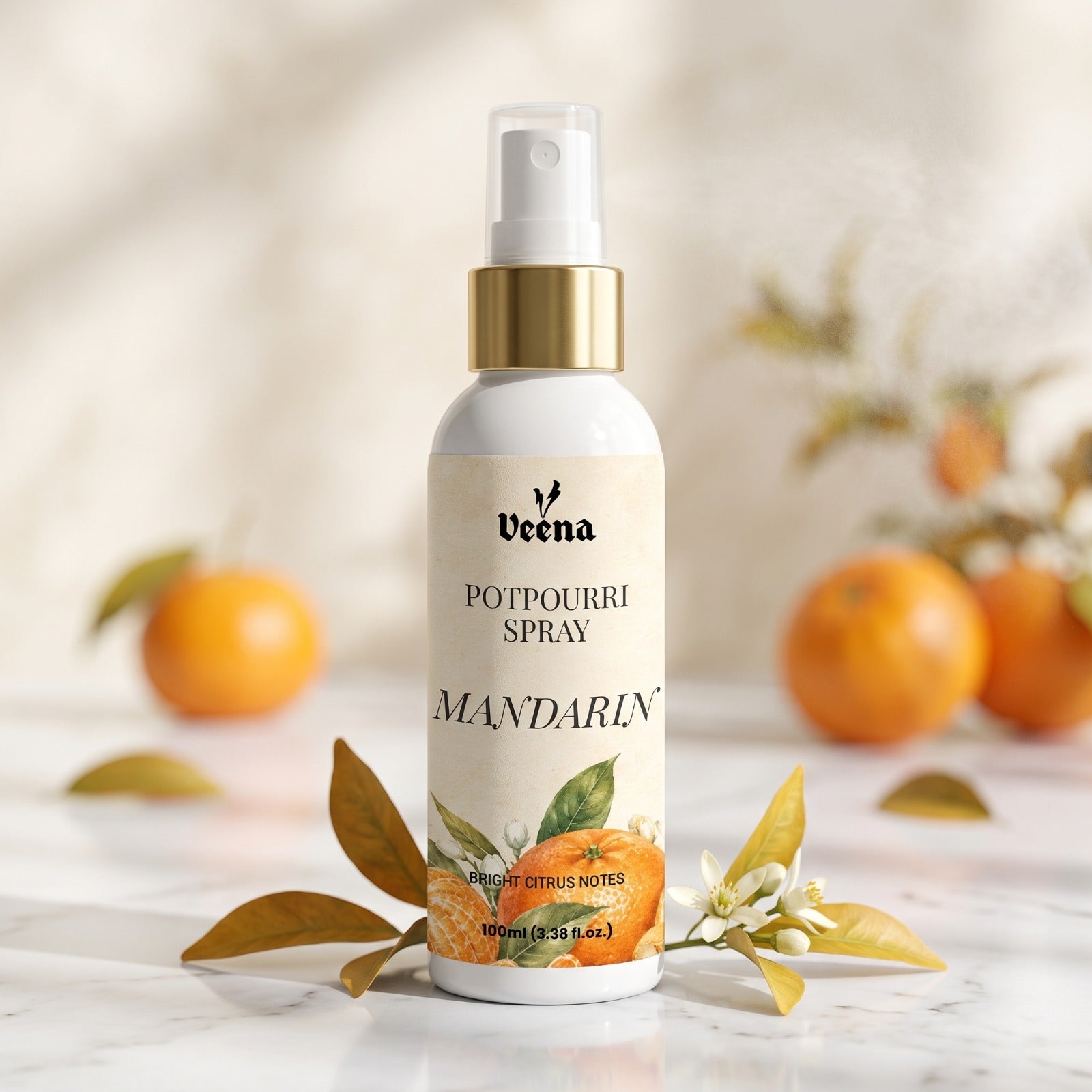 Veena Mandarin Potpourri Spray 100ml bottle displayed on a white marble table with fresh oranges and leaves – Bright Citrus Notes Home Fragrance.
