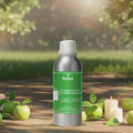 Veena Green Apple Fragrance for Candle Making 100ml aluminum bottle standing on a sunny outdoor path surrounded by fresh green apples and burning white candles.