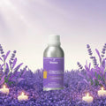 Veena Lavender Fragrance for Candle Making 100ml aluminum bottle standing inside a lush purple lavender field under sunlight surrounded by burning white candles.